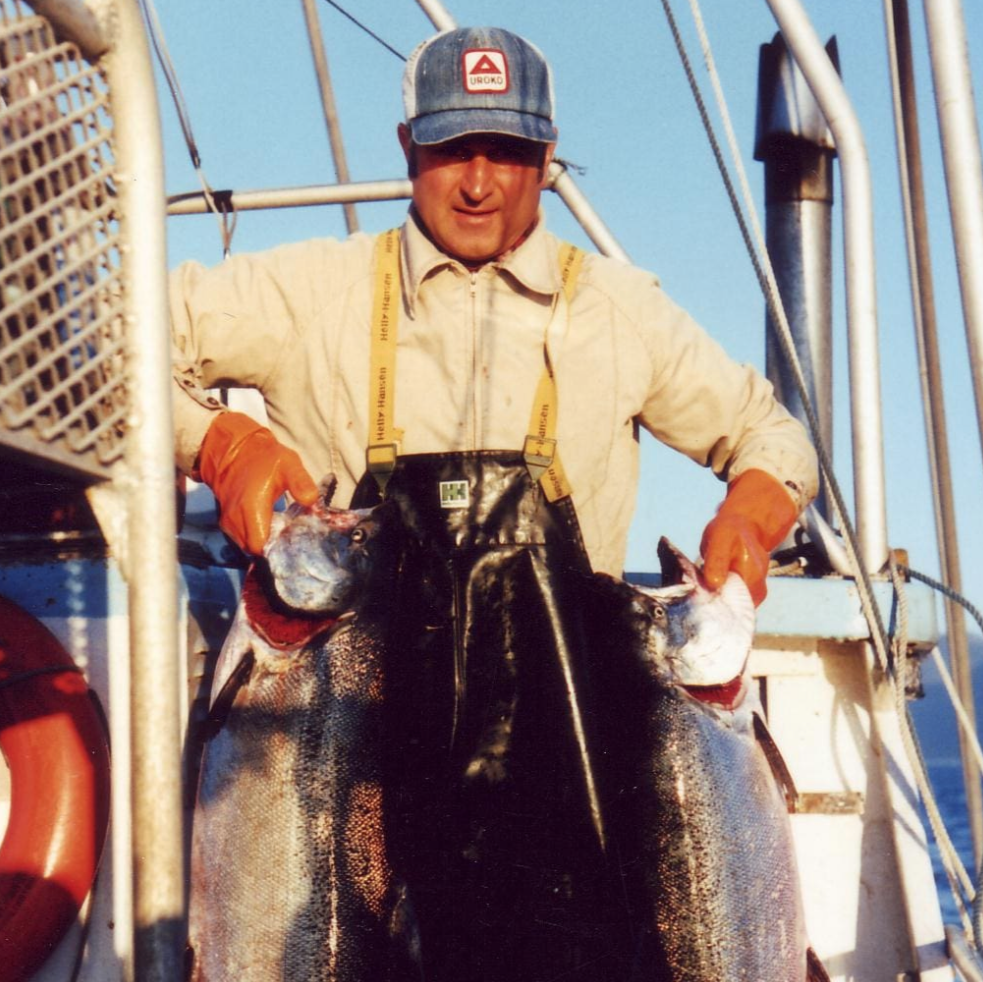 Man on a boat holding two large fish with a clear blue sky background- skipper otto x treatos box partnership