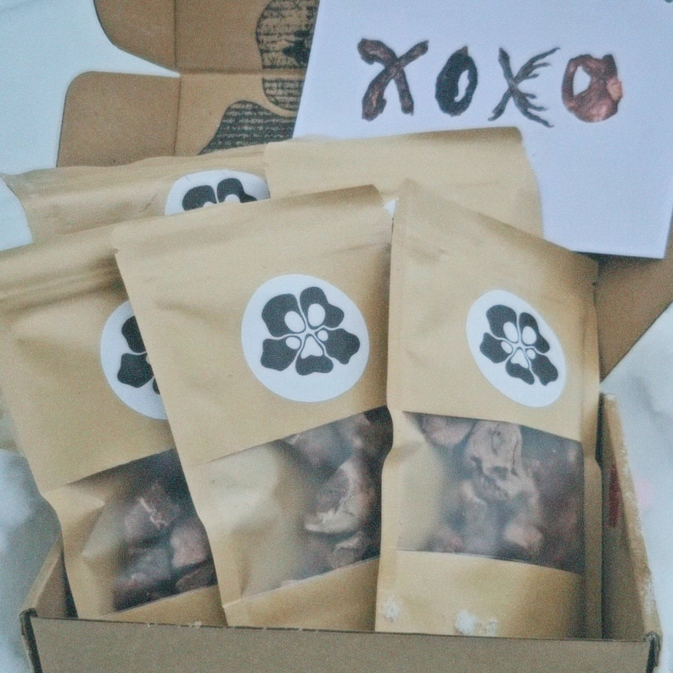 Box of brown paper treatos box bags with treatosbox brand labels on a snowy surface