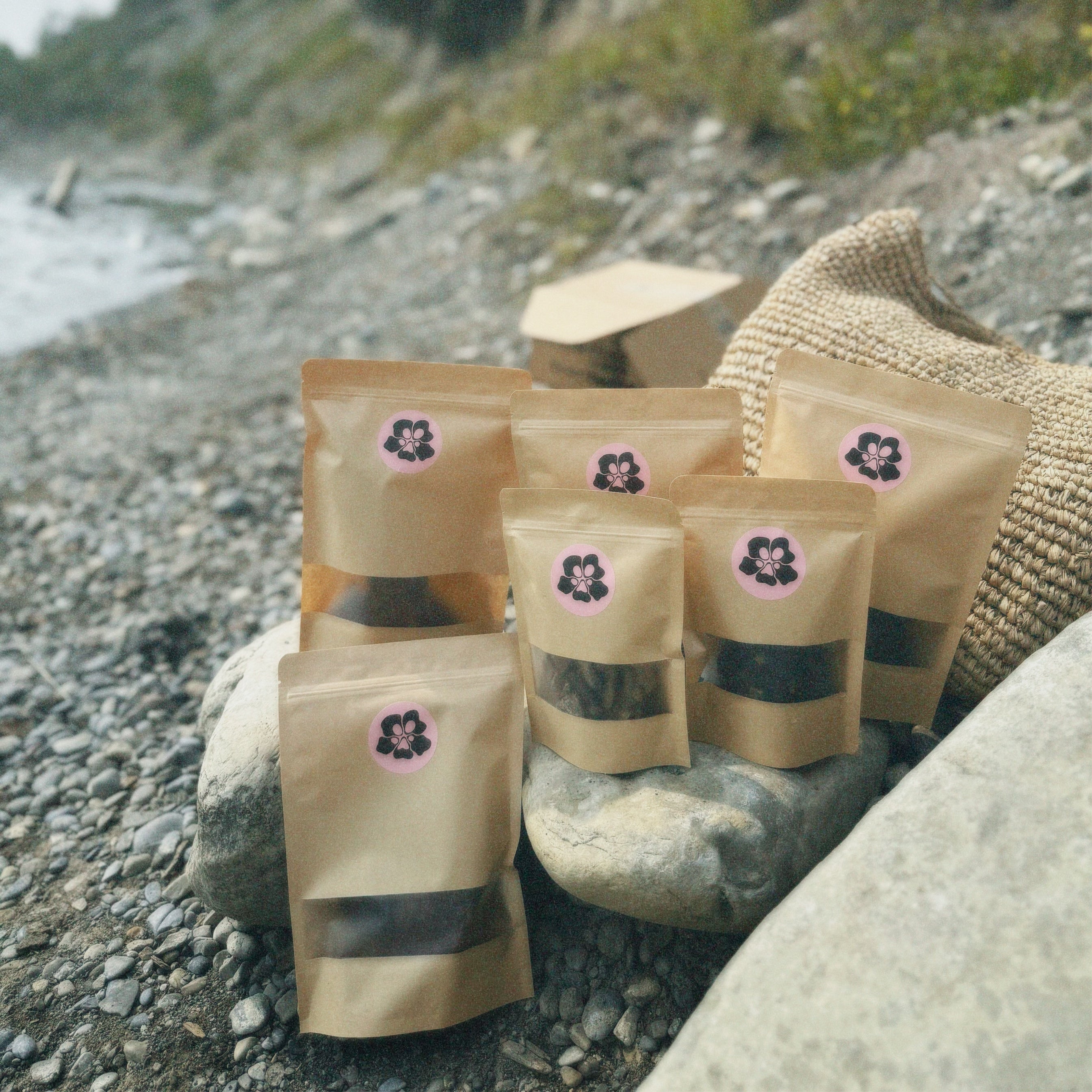 treatos box bags with floral labels on a rocky beach with trees in the background